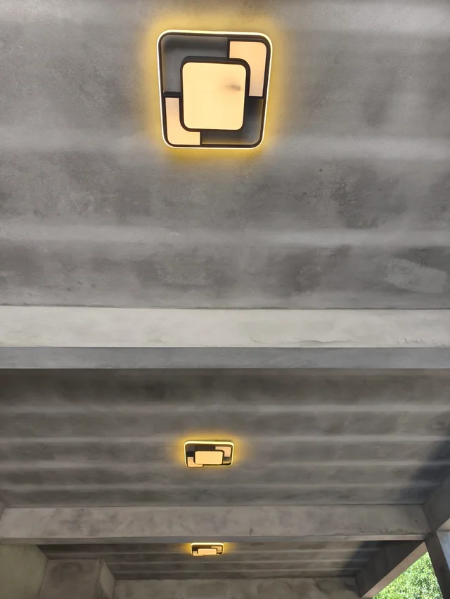 Sequência de luminárias acesas no teto de uma varanda.