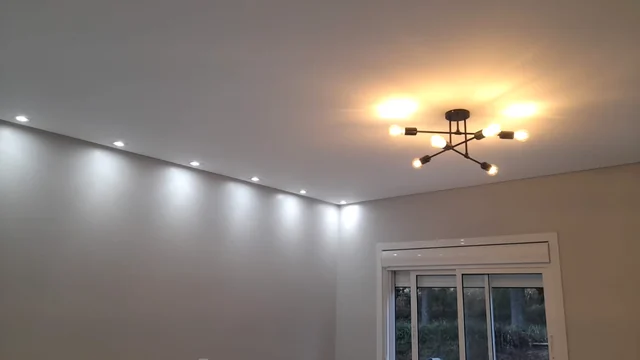 Luminária central e pequenos pontos de luz no teto de uma sala.