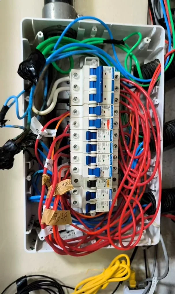Antes do serviço: quadro elétrico aberto, com disjuntores e muitos fios vermelhos soltos.
